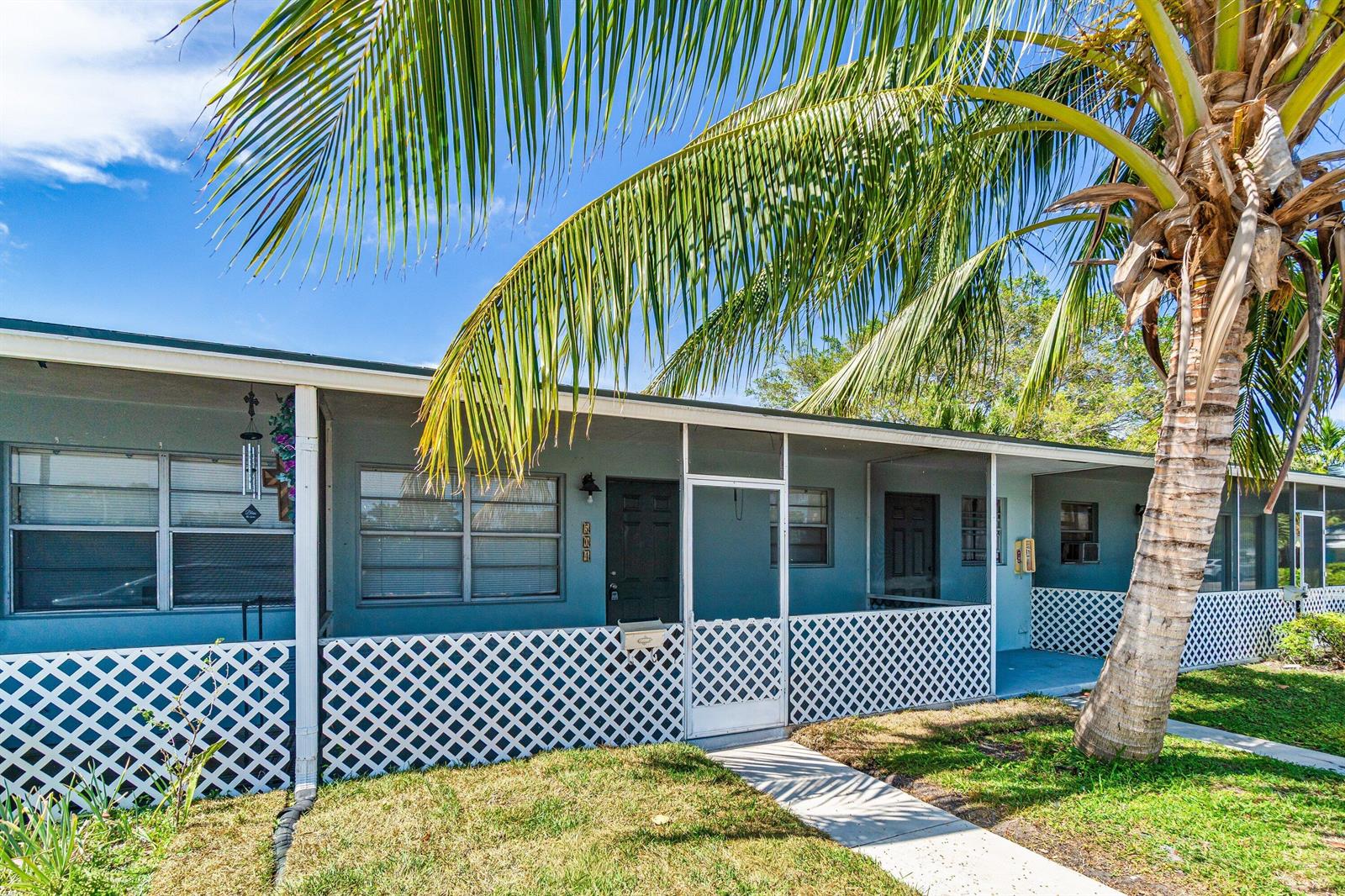 A single-story building with a covered porch, lattice skirting, and a large palm tree — 504 9th Avenue N # 508, FL 33460, FL