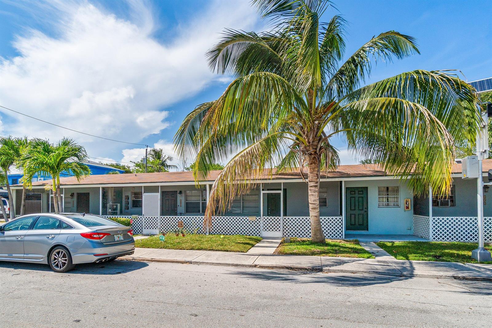 A single-story gray apartment building features a palm tree and a parked silver sedan — 504 9th Avenue N # 508, FL 33460, FL