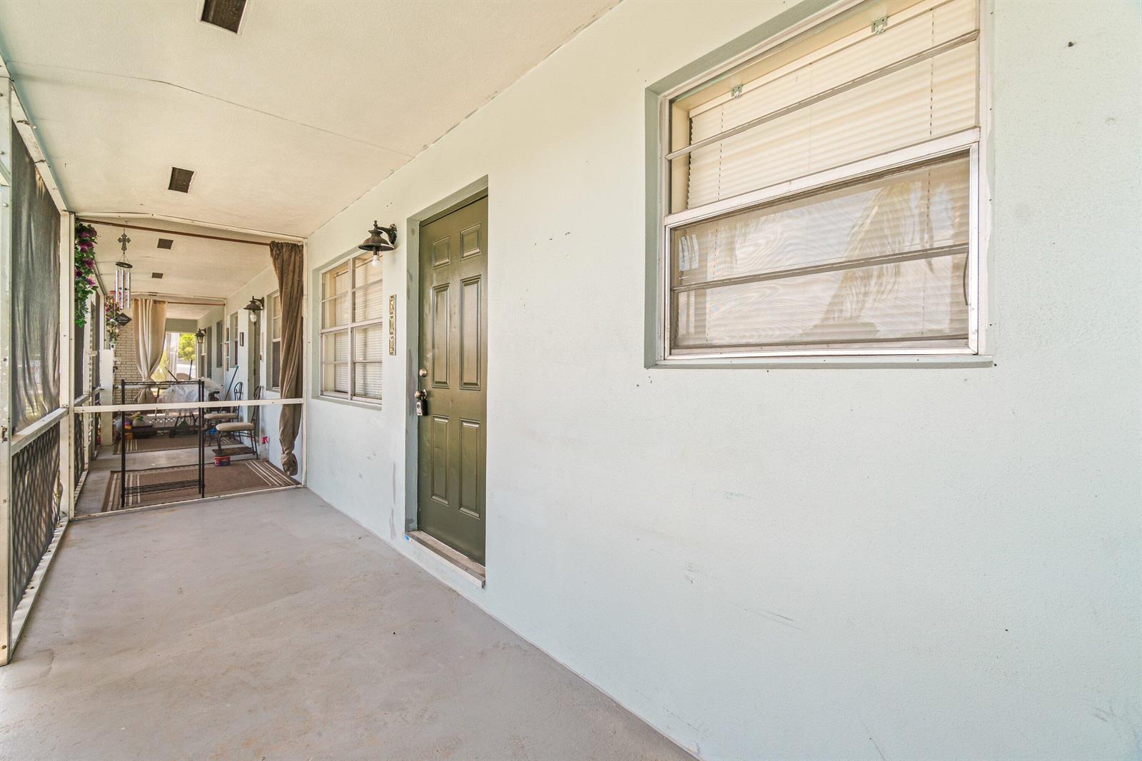 A covered patio with a green door, a window, and a screened-in enclosure — 504 9th Avenue N # 508, FL 33460, FL