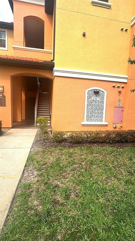 An exterior view of an orange apartment building with a staircase and a decorative window — 5483 VINELAND ROAD UNIT 10309, ORLANDO, FL