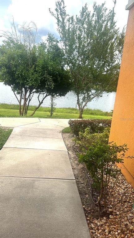 A concrete walkway leads past a landscaped garden toward a lake behind a building — 5483 VINELAND ROAD UNIT 10309, ORLANDO, FL