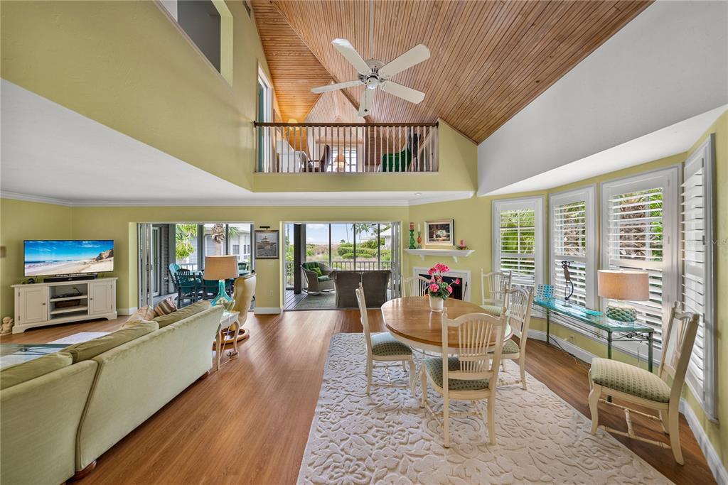 A living and dining area with vaulted wood ceilings, a loft, and a screened patio — 12 SEAWATCH DRIVE, BOCA GRANDE, FL