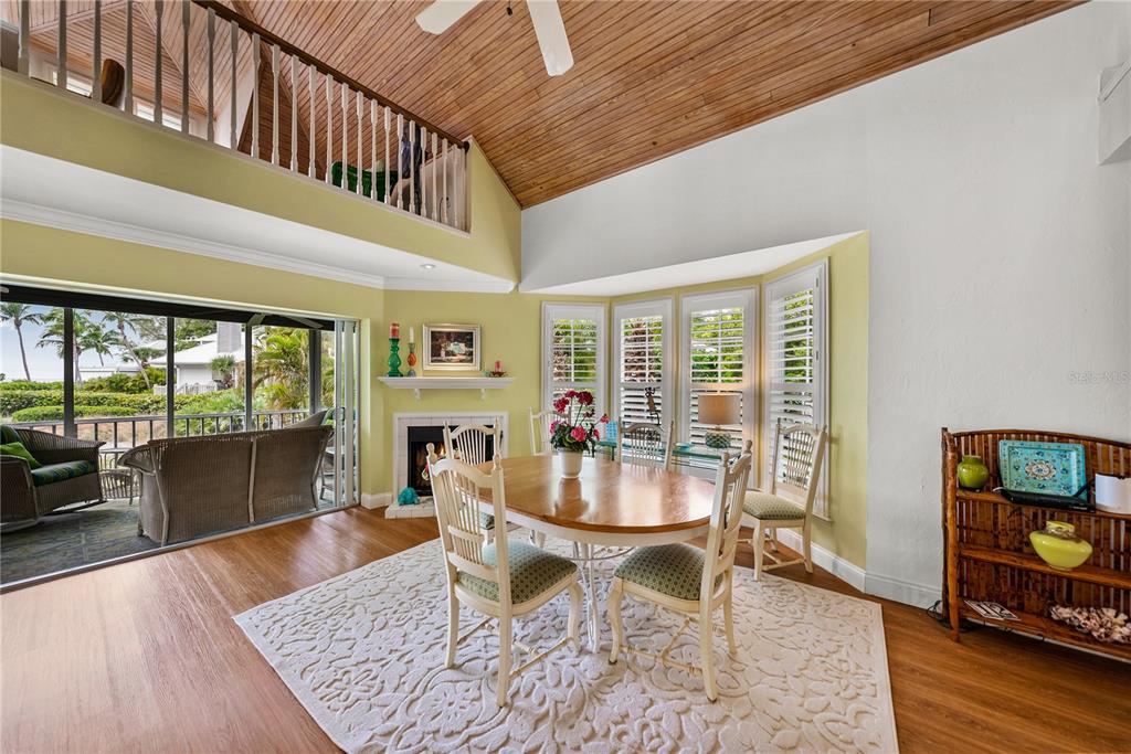 A dining room with a vaulted wood ceiling, fireplace, and sliding doors to a patio — 12 SEAWATCH DRIVE, BOCA GRANDE, FL