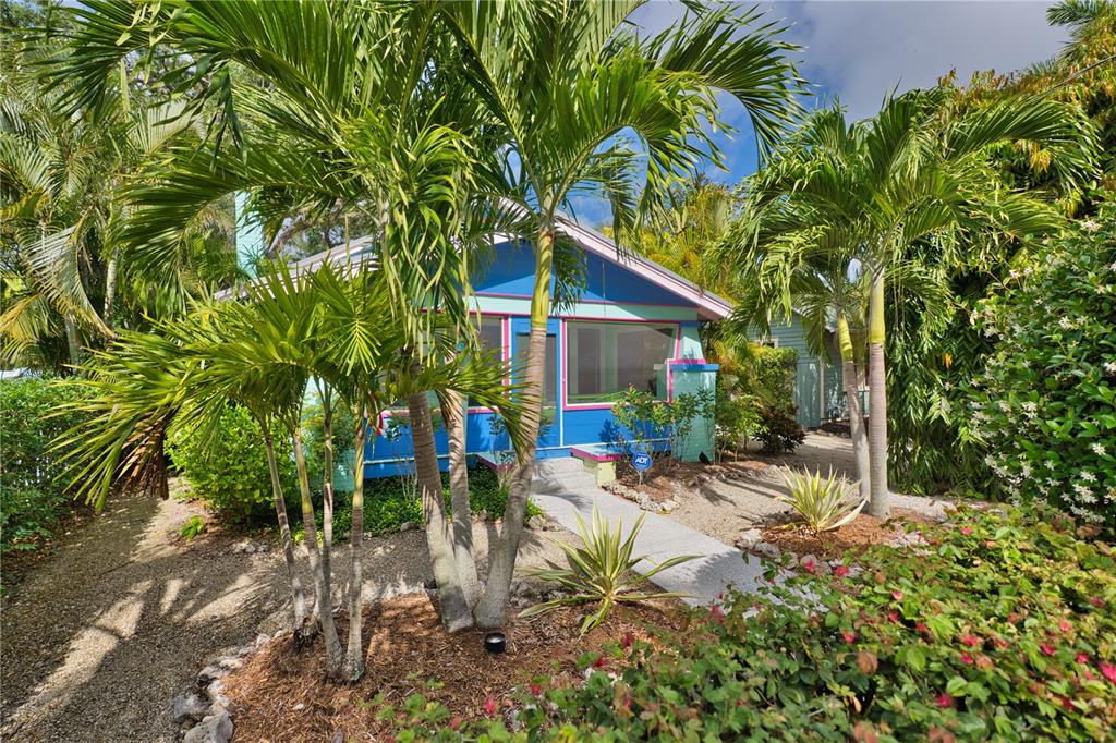 A blue cottage with a screened porch is surrounded by palm trees and tropical landscaping — 642 OHIO PLACE, SARASOTA, FL