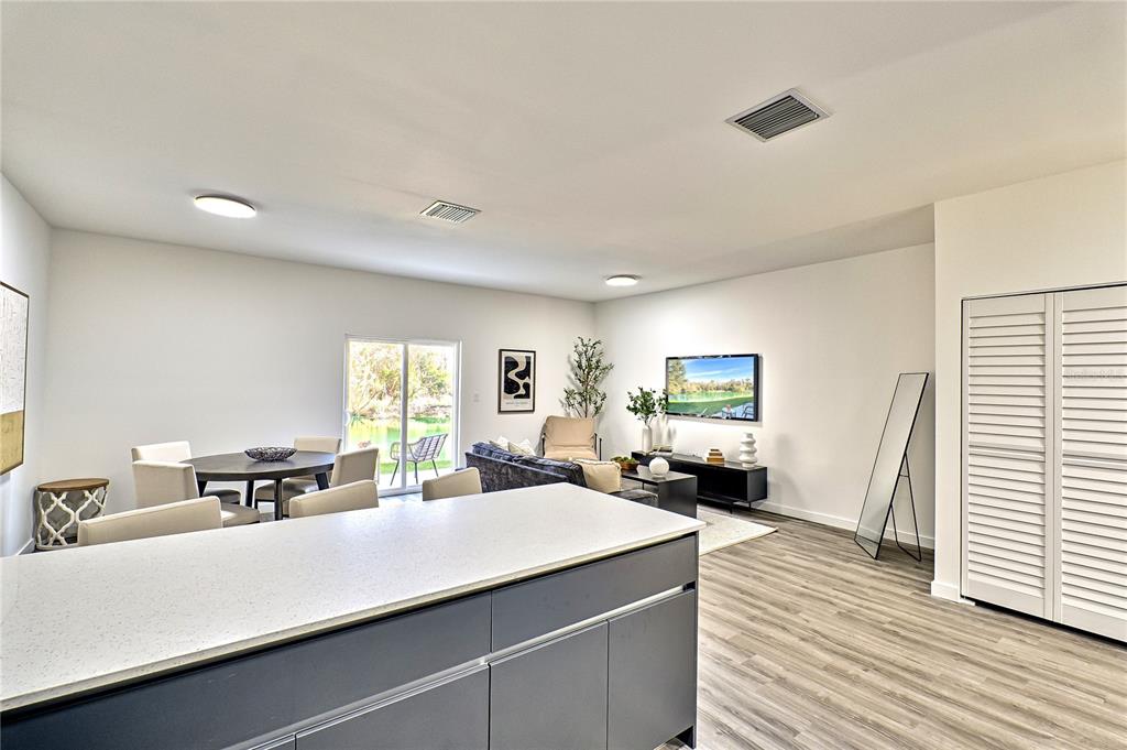 A modern open-concept living and dining area features a kitchen island, light flooring, and sliding doors — 1591 NW 29TH ROAD UNIT 4, GAINESVILLE, FL