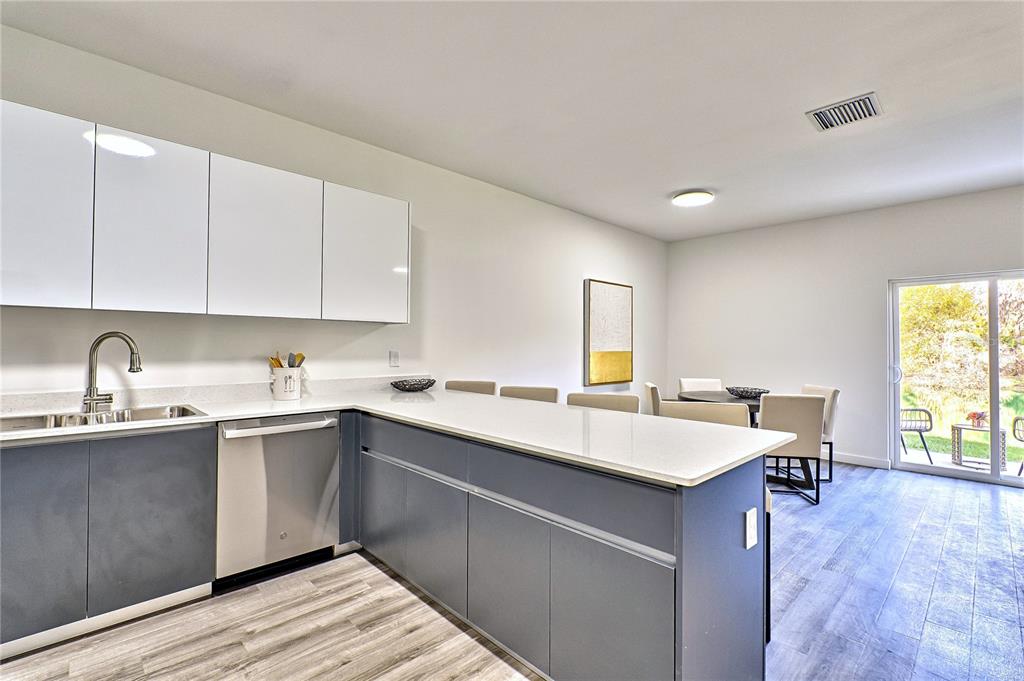 A modern kitchen features dark gray lower cabinets, white upper cabinets, and a breakfast bar — 1591 NW 29TH ROAD UNIT 4, GAINESVILLE, FL