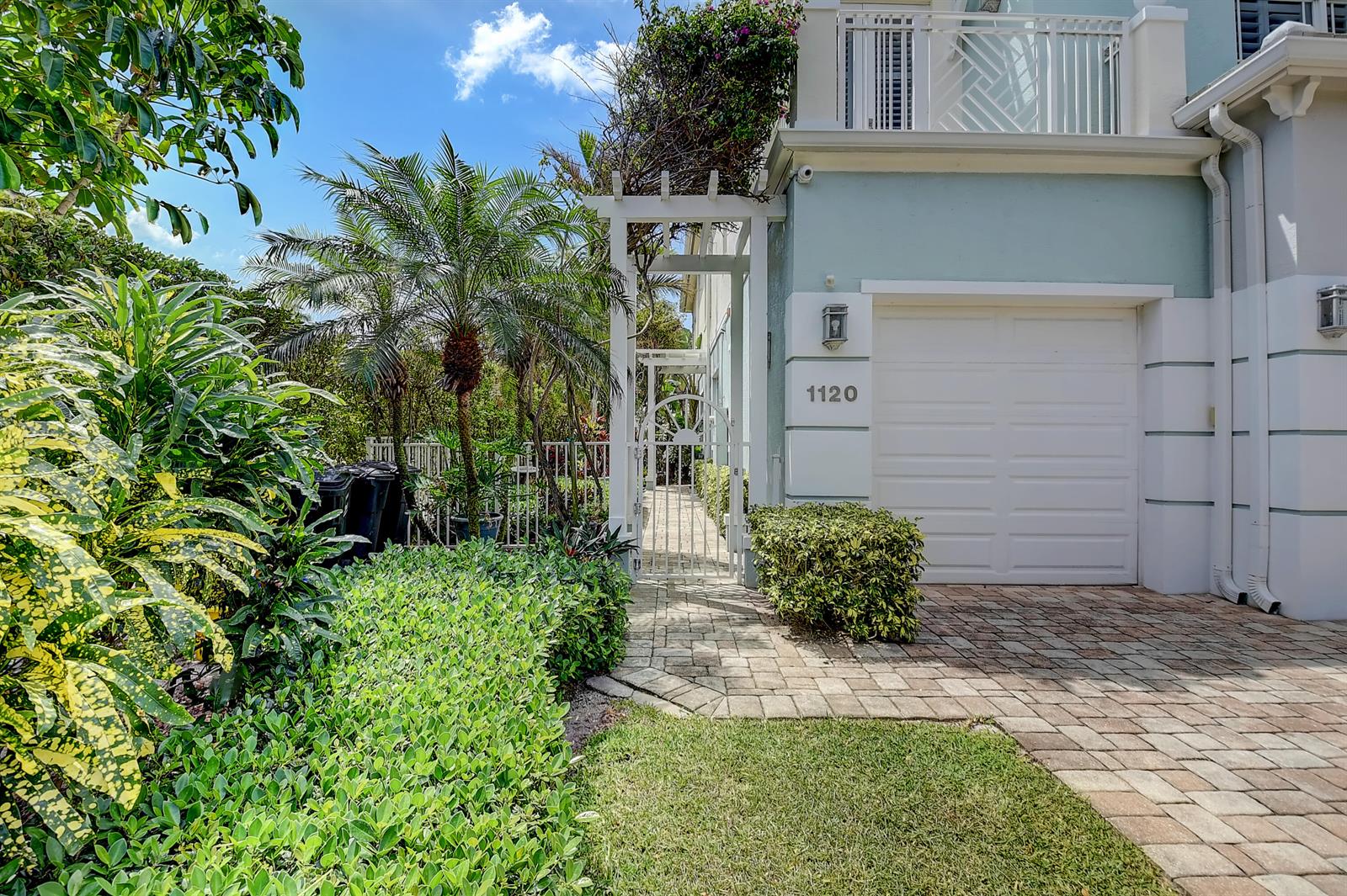 A paved walkway leads to a white gate beside a house with a garage — 1120 Ocean Terrace, Delray Beach FL 33483, DELRAY BEACH, FL