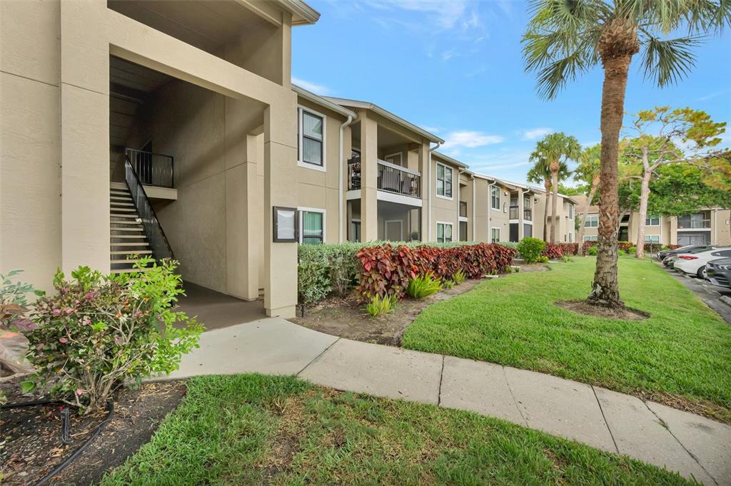 An exterior view of a multi-story apartment building with a sidewalk, landscaping, and parking area — 4065 CROCKERS LAKE BOULEVARD UNIT 14, SARASOTA, FL
