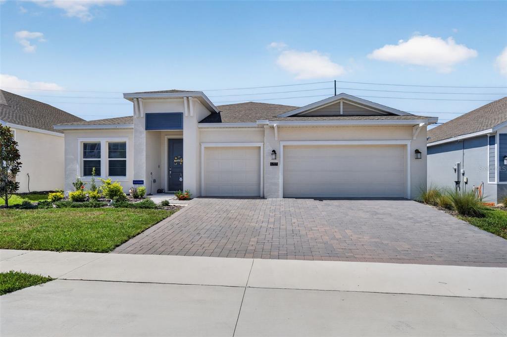 A single-story house with a three-car garage, paved driveway, and light-colored stucco exterior — 1777 RIDER RAIN LANE, APOPKA, FL