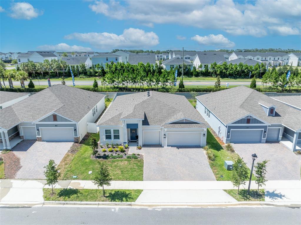 An aerial view shows three suburban houses with paved driveways and gray shingled roofs — 1777 RIDER RAIN LANE, APOPKA, FL
