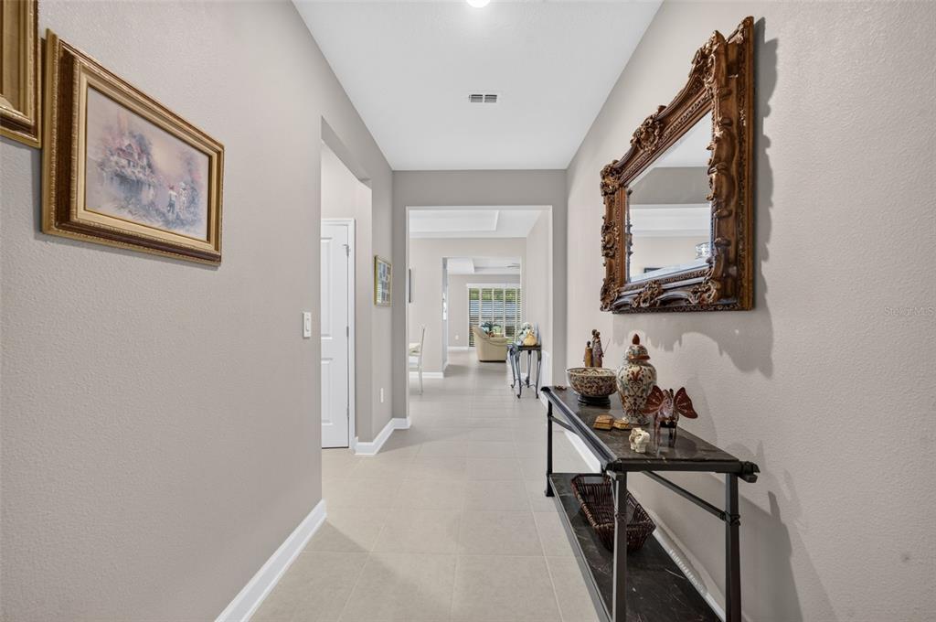 A hallway with light tile floors, a console table, a mirror, and framed wall art — 1777 RIDER RAIN LANE, APOPKA, FL
