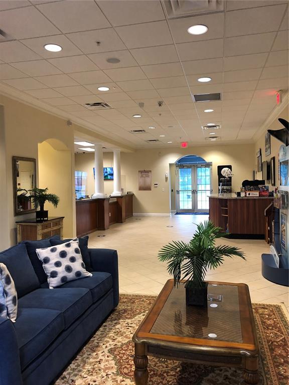 A waiting area features a blue sofa, a glass-top coffee table, and a reception desk — 13427 BLUE HERON BEACH DRIVE UNIT 406, ORLANDO, FL