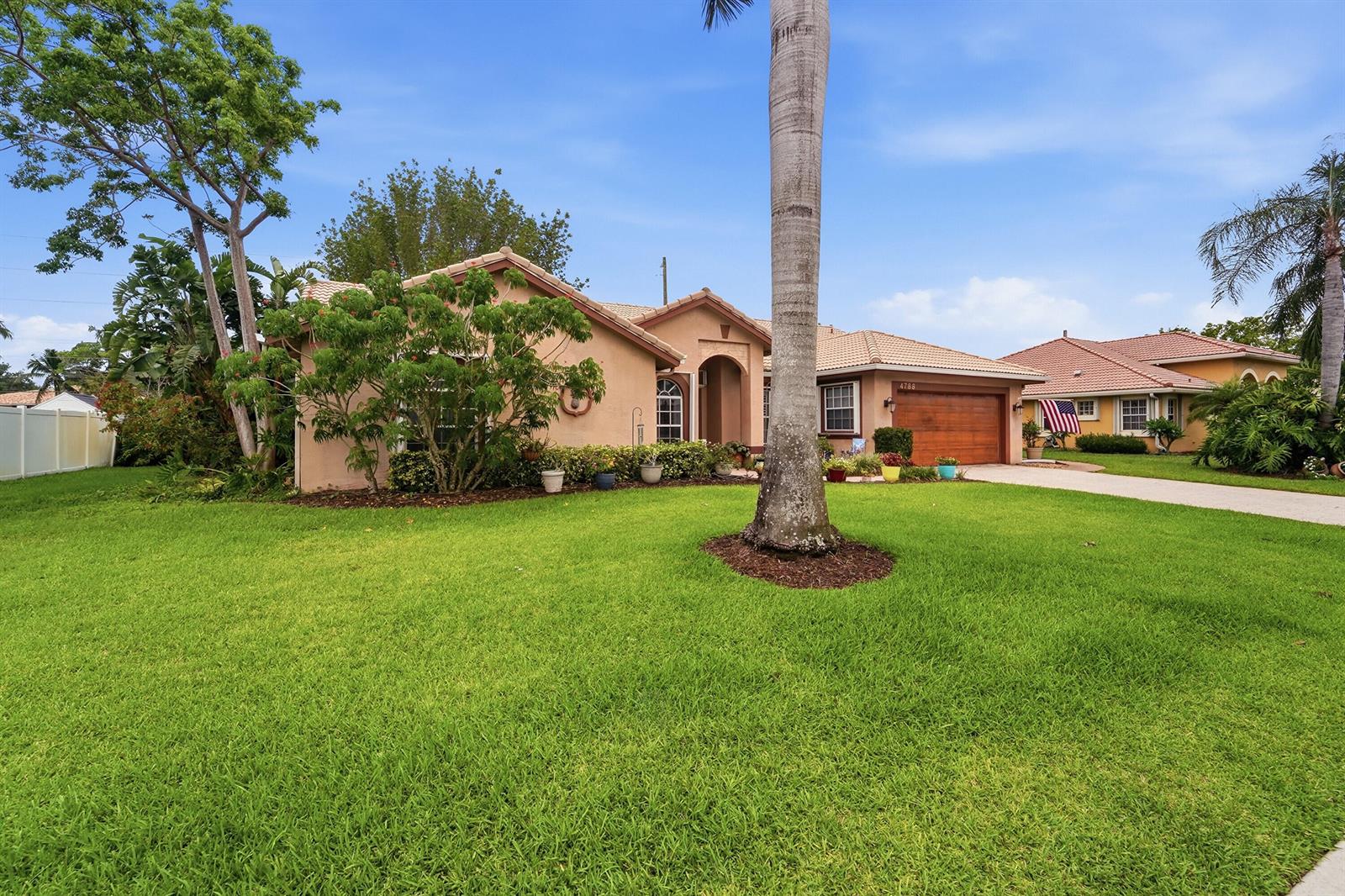 A single-story tan house with a tile roof, wooden garage door, and a front lawn — 4788 S Cypress Dr Drive S, Boynton Beach FL 33436, BOYNTON BEACH, FL