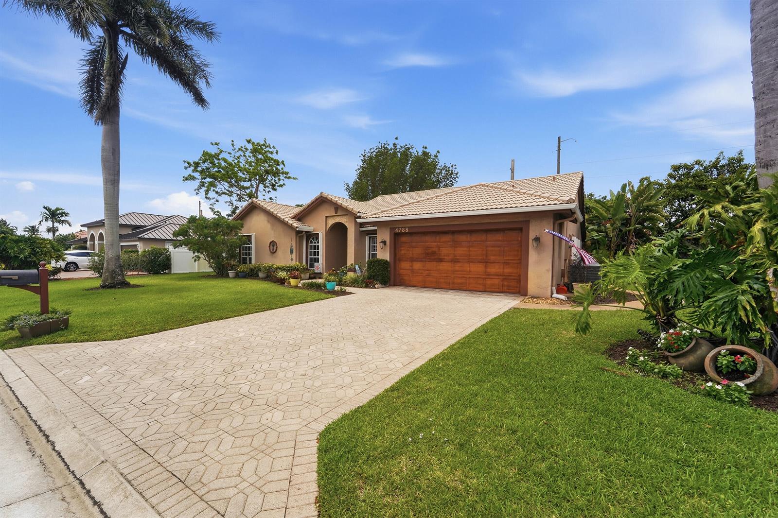 A single-story house with a tiled roof, a wooden garage door, and a paved driveway — 4788 S Cypress Dr Drive S, Boynton Beach FL 33436, BOYNTON BEACH, FL