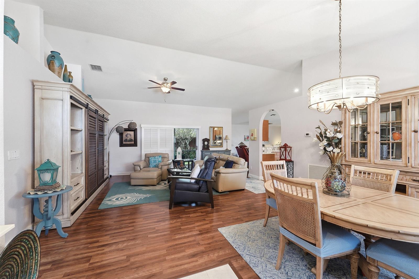 An open-concept living and dining area features wood-look flooring, vaulted ceilings, and a ceiling fan — 4788 S Cypress Dr Drive S, Boynton Beach FL 33436, BOYNTON BEACH, FL