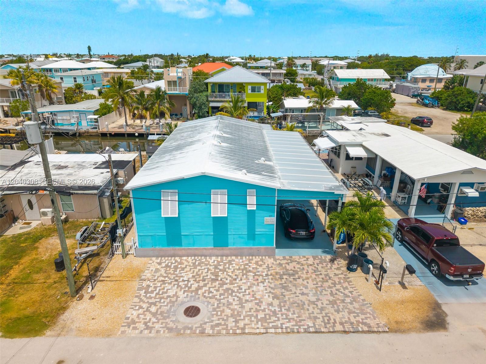 An aerial view shows a bright blue house with a metal roof and a paved driveway — 837 91st Court Ocean, Marathon FL 33050, MARATHON, FL