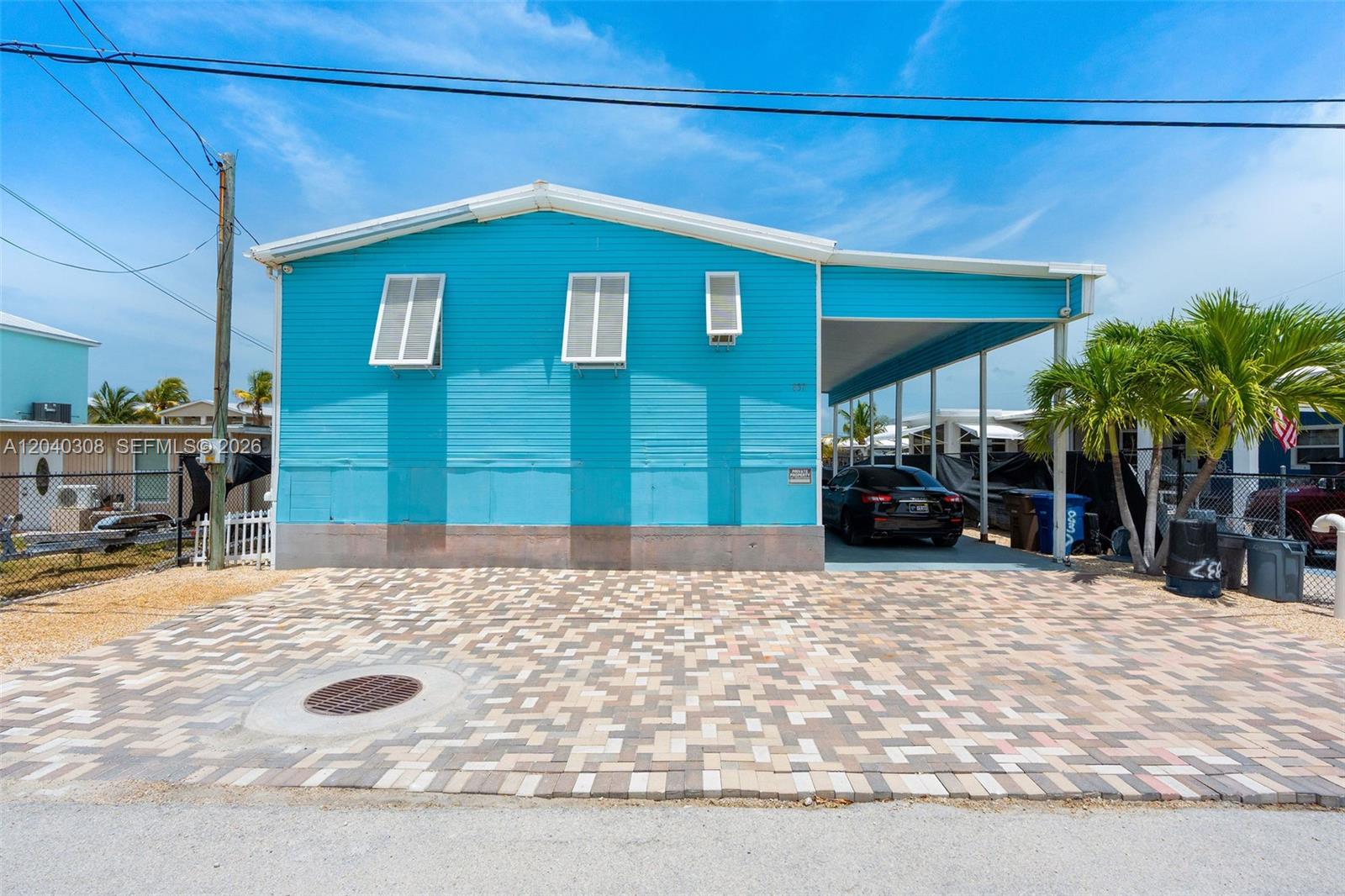A bright blue manufactured home features a paved driveway, a carport, and white shutters — 837 91st Court Ocean, Marathon FL 33050, MARATHON, FL