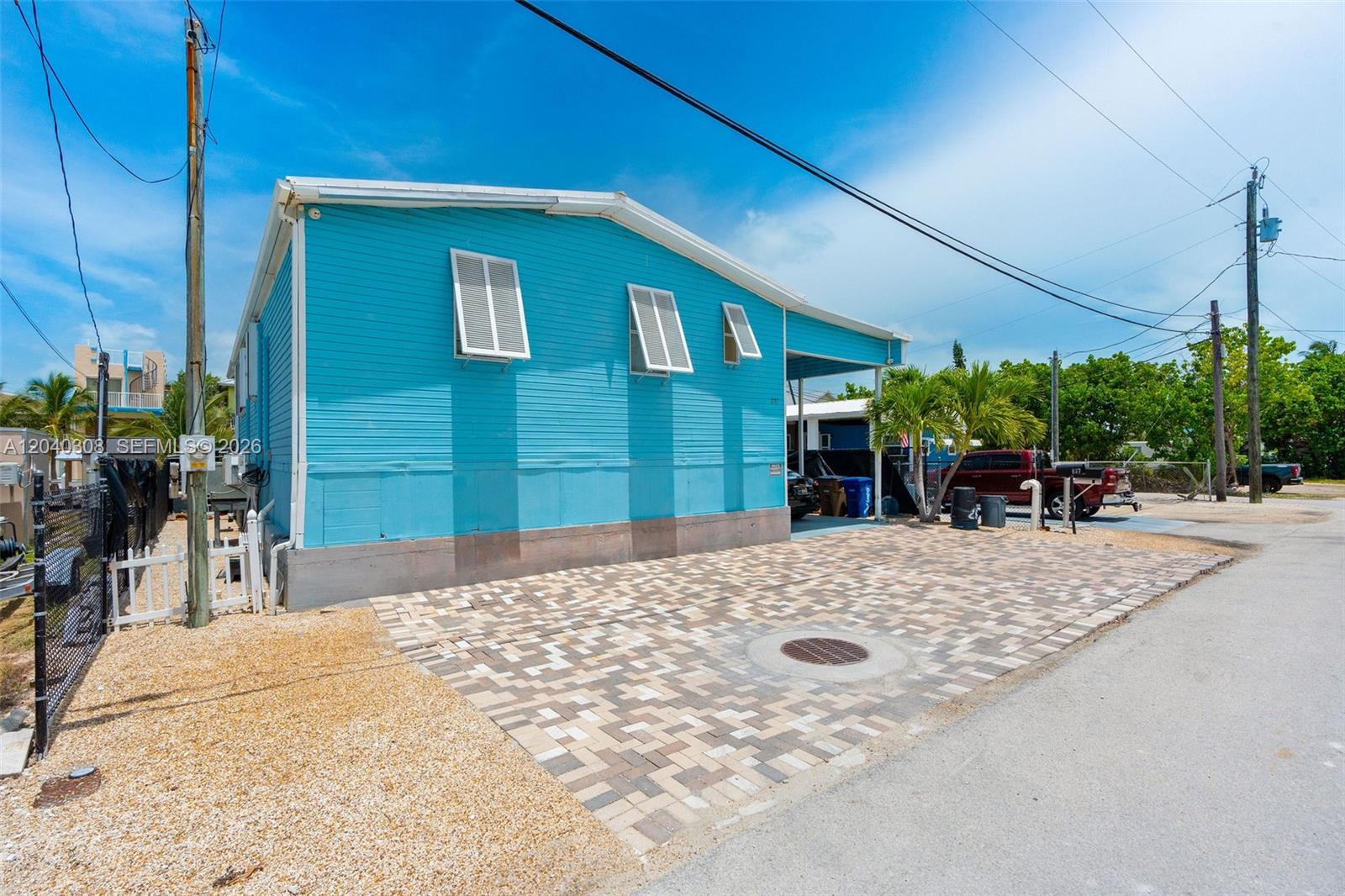 A bright blue mobile home features a paved driveway and a covered carport area — 837 91st Court Ocean, Marathon FL 33050, MARATHON, FL