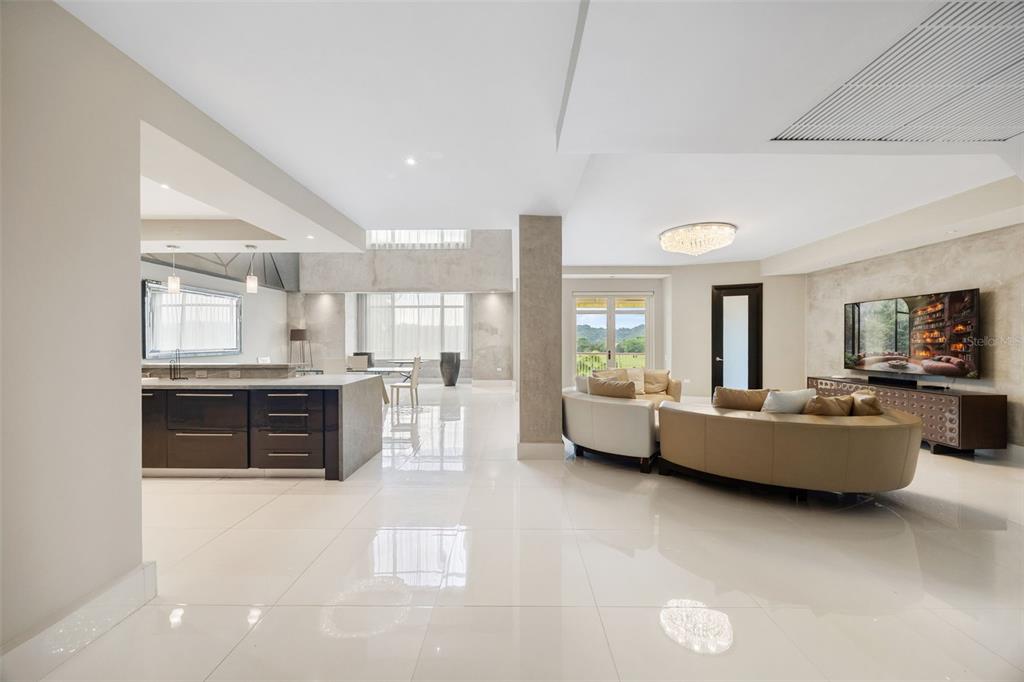A modern open-concept living area features a kitchen, curved sofa, and large windows — Carr. 693 Km.10 HM 7 PLANTATION VILLAGE DRIVE UNIT 1202, DORADO, PR