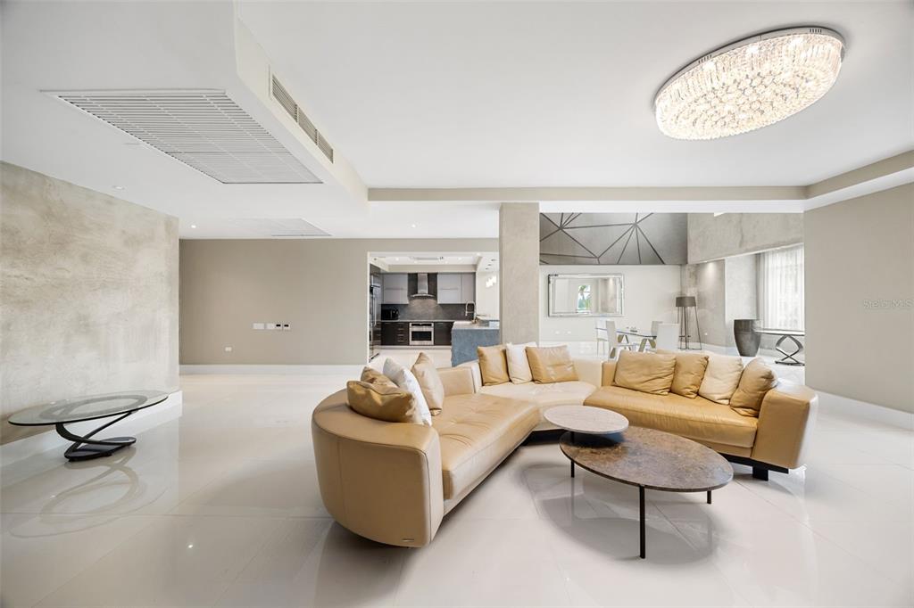 A modern living room features a curved tan sectional sofa, marble floors, and a crystal chandelier — Carr. 693 Km.10 HM 7 PLANTATION VILLAGE DRIVE UNIT 1202, DORADO, PR