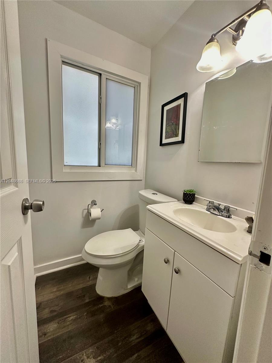 A small bathroom features a white vanity, a toilet, and dark wood-look flooring — 3611 OAK AV, Miami FL 33133, MIAMI, FL