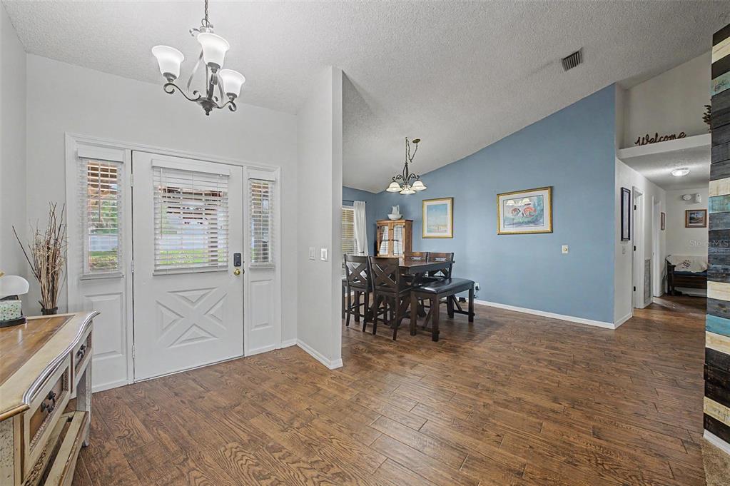 An entryway with wood-look flooring leads into a dining area with a blue accent wall — 3916 BROOMSEDGE LANE, VALRICO, FL