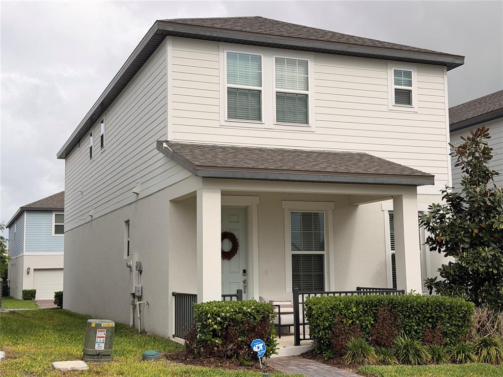 A two-story house with light-colored siding, a front porch, and a small landscaped yard — 4863 LACEWING DRIVE, WINTER GARDEN, FL