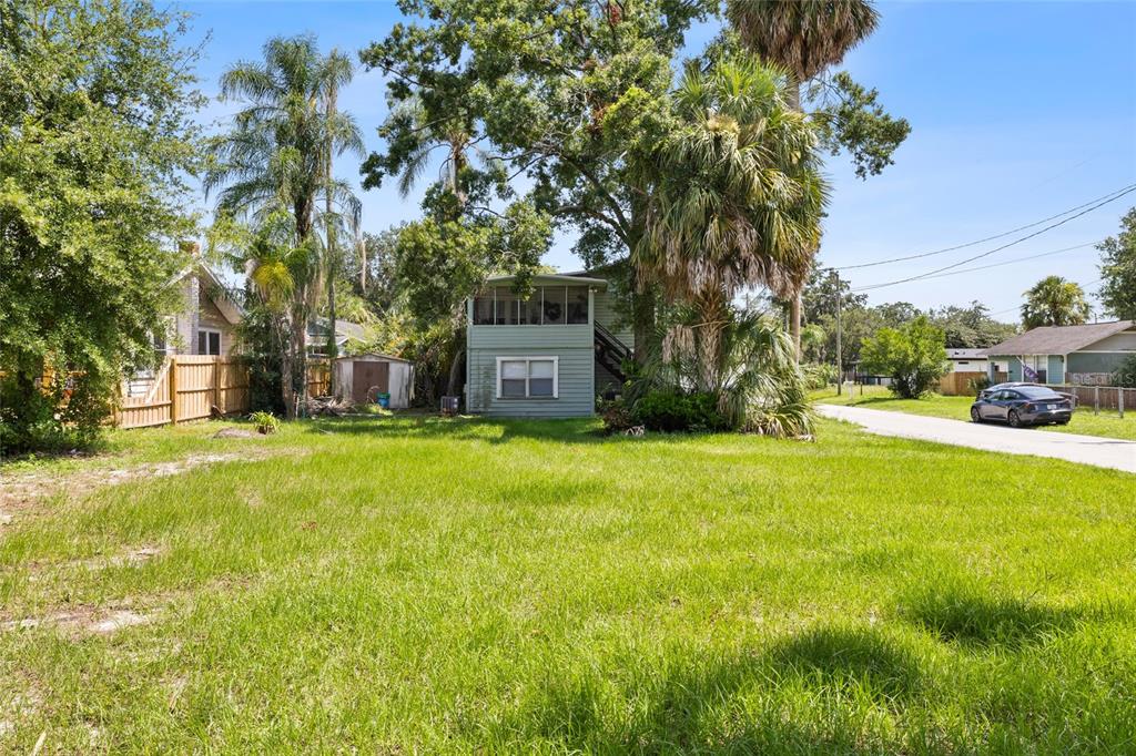 A two-story light green house with a screened porch stands behind a grassy yard — 128 W NORTH STREET, TAMPA, FL