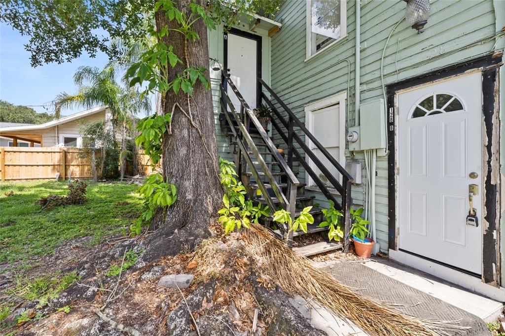 An exterior view of a house with a wooden staircase leading to an upper entrance — 128 W NORTH STREET, TAMPA, FL