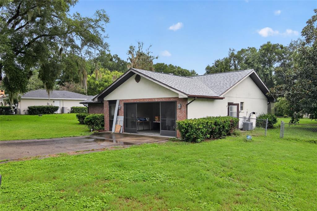 A detached garage with a screened-in opening and a brick facade sits on a grassy lot — 4279 E ARLINGTON STREET, INVERNESS, FL