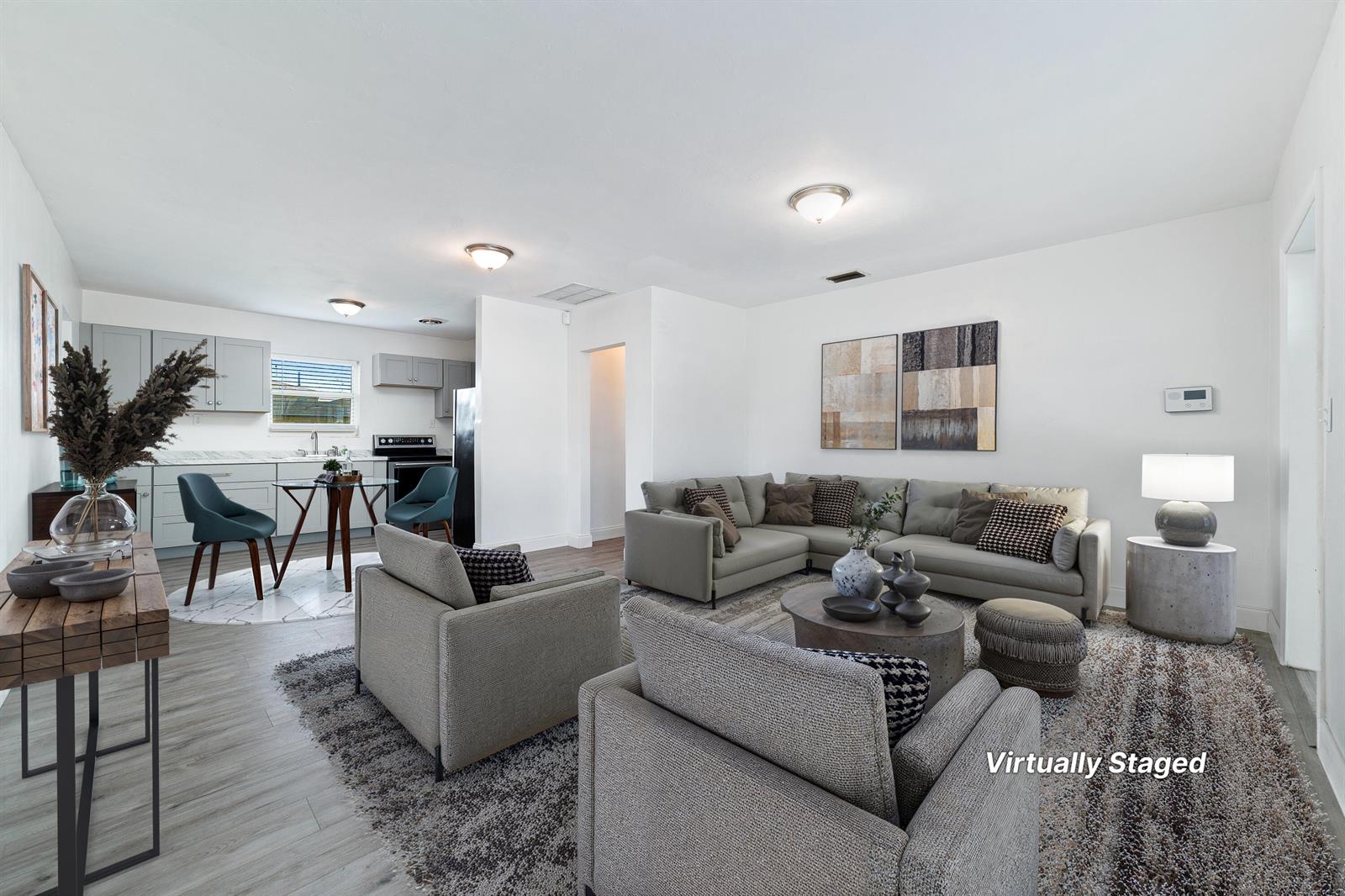A virtually staged open-concept living room and kitchen with light wood-look flooring — 317 NW 14th Street, Belle Glade FL 33430, BELLE GLADE, FL
