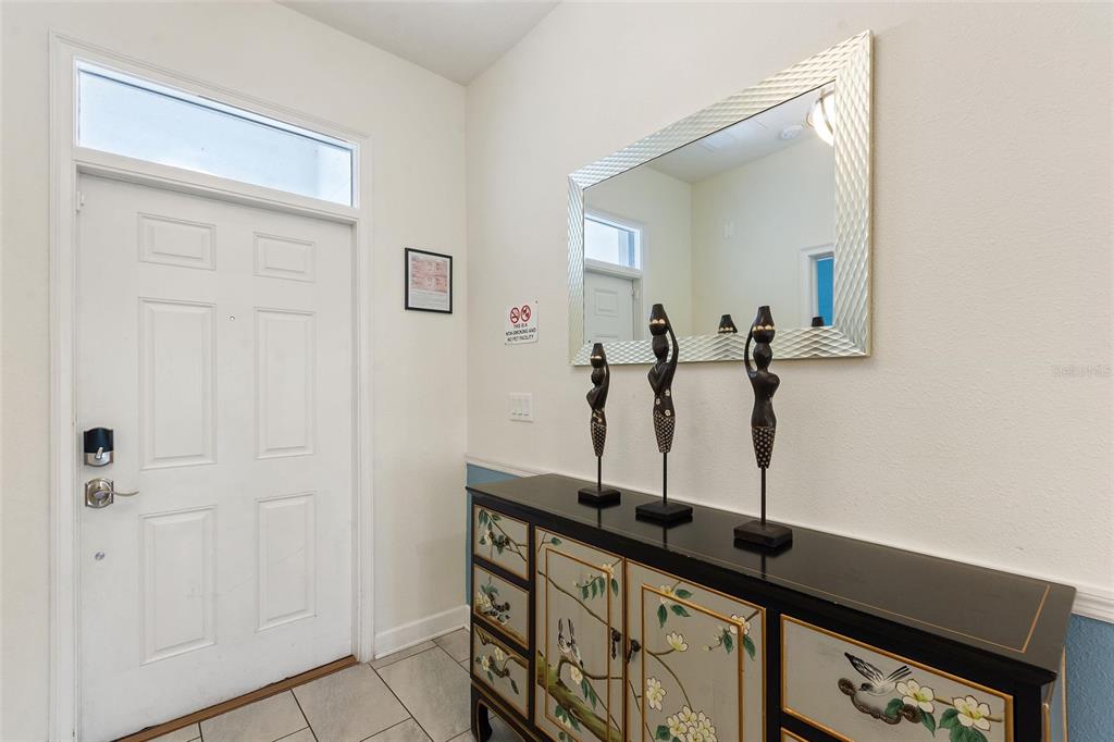 An entryway features a white door, a patterned console table, and a large wall mirror — 1524 FLANGE DRIVE, DAVENPORT, FL