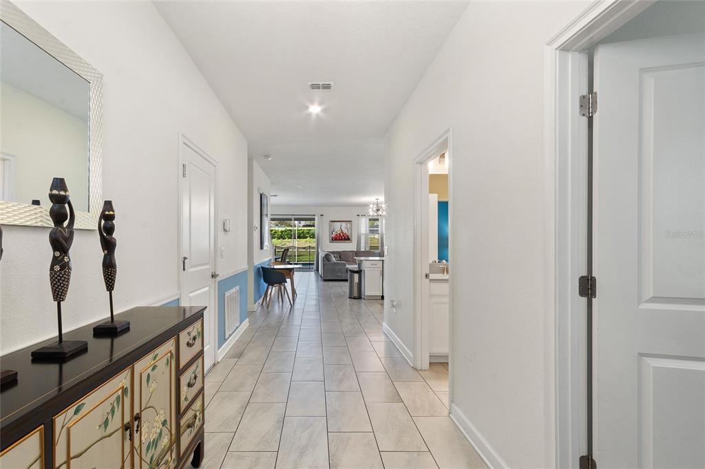 A tiled hallway leads from a foyer with decorative statues toward an open-concept living area — 1524 FLANGE DRIVE, DAVENPORT, FL