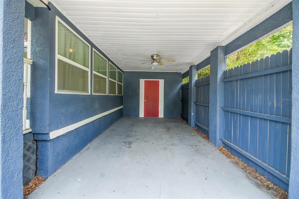 A covered carport with a concrete floor, blue exterior walls, and a red door — 301 S HAMPTON AVENUE, ORLANDO, FL