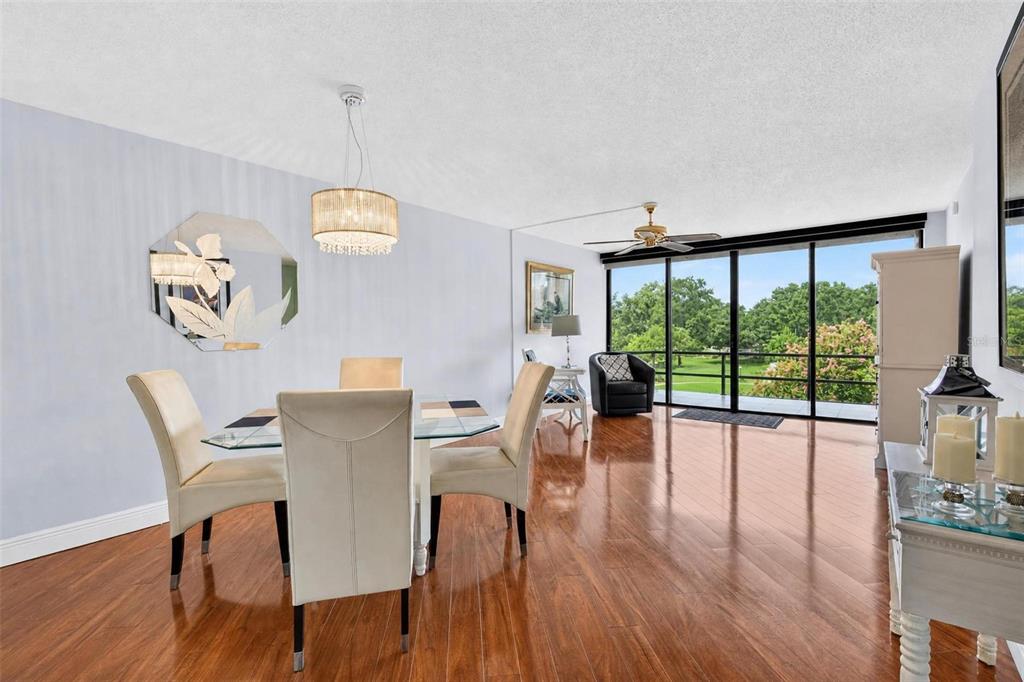 A dining area with a glass table, upholstered chairs, hardwood floors, and floor-to-ceiling windows — 14130 ROSEMARY LANE UNIT 3311, LARGO, FL