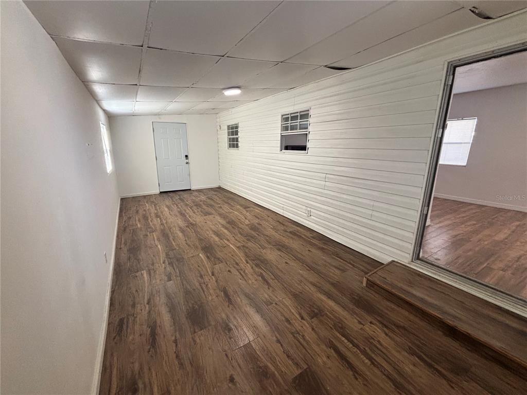 An interior room features wood-look flooring, white horizontal siding walls, and a drop ceiling — 5480 PINELAND AVENUE, PORT ORANGE, FL