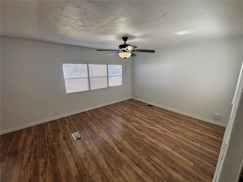 An empty bedroom features white walls, a ceiling fan, and wood-look flooring — 5480 PINELAND AVENUE, PORT ORANGE, FL