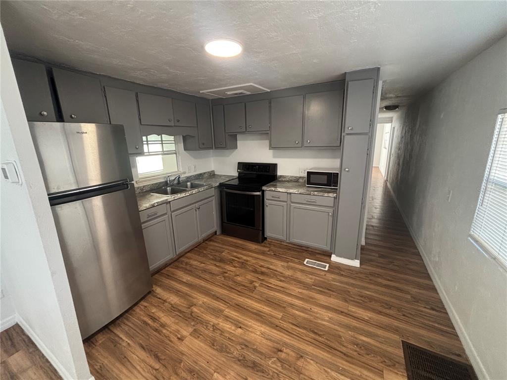 A kitchen features grey cabinets, stainless steel appliances, laminate countertops, and wood-look flooring — 5480 PINELAND AVENUE, PORT ORANGE, FL