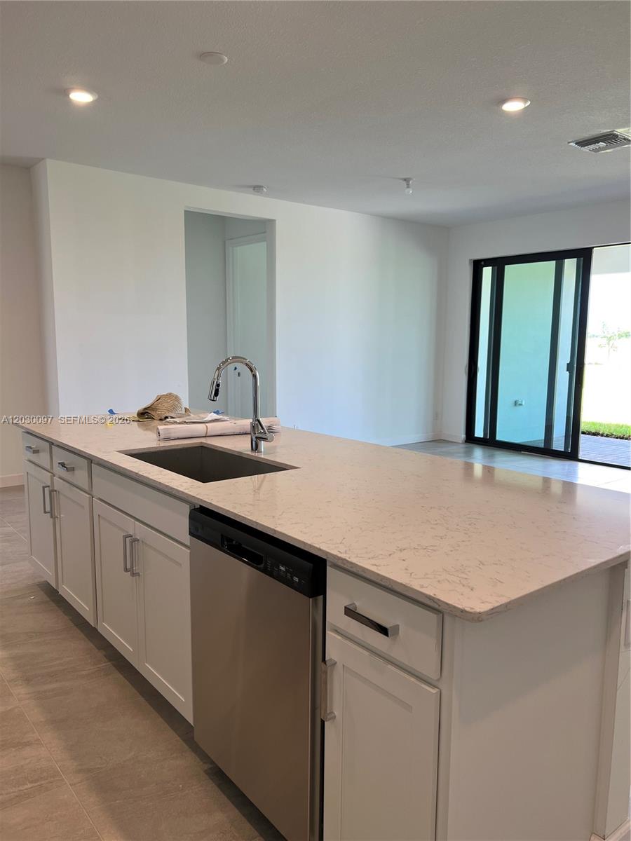 A modern kitchen island with a stainless steel dishwasher and sink sits in an open room — 19667 Rugged Trunk Trl # 0, Loxahatchee FL 33470, LOXAHATCHEE, FL