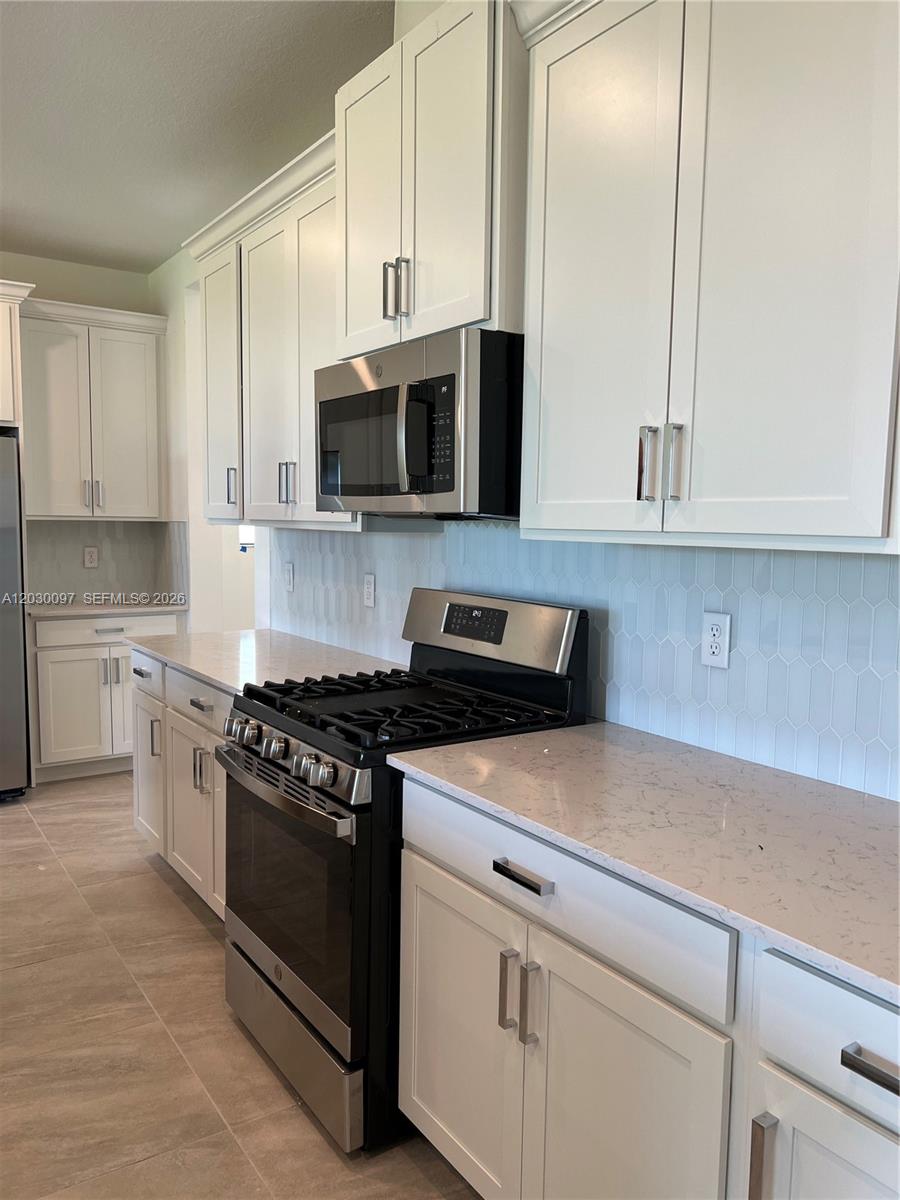 A kitchen features white cabinets, stainless steel appliances, a gas range, and light-colored countertops — 19667 Rugged Trunk Trl # 0, Loxahatchee FL 33470, LOXAHATCHEE, FL
