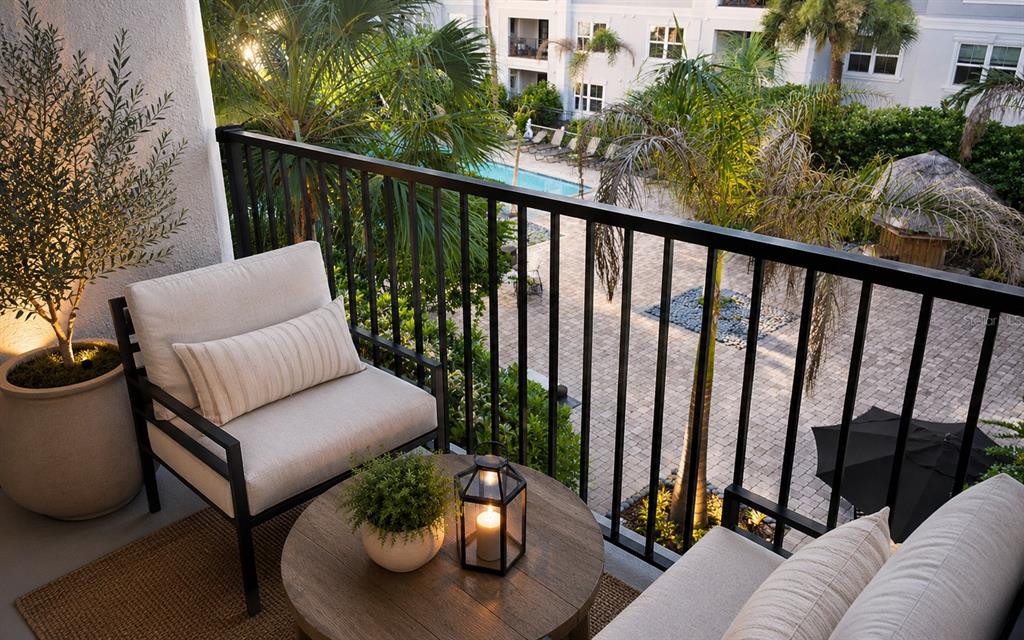 A balcony features two chairs, a round wooden table, and a view of a pool — 204 E SOUTH STREET UNIT 3060, ORLANDO, FL