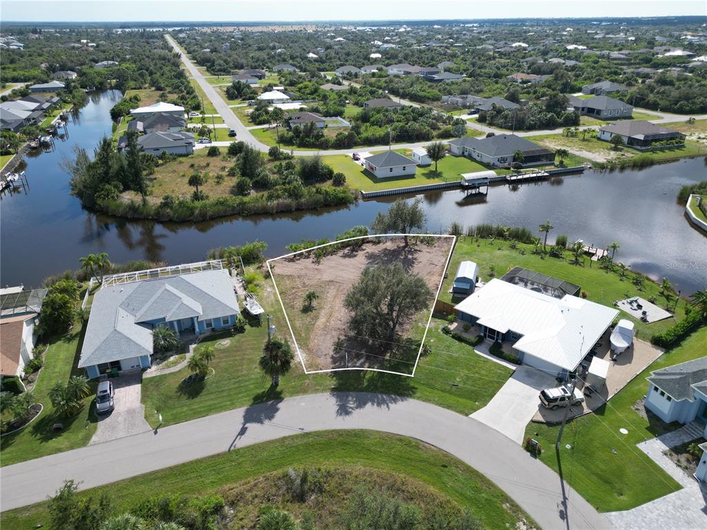 An aerial view shows a vacant waterfront lot situated between two existing residential homes — 9588 NASTRAND CIRCLE, PORT CHARLOTTE, FL