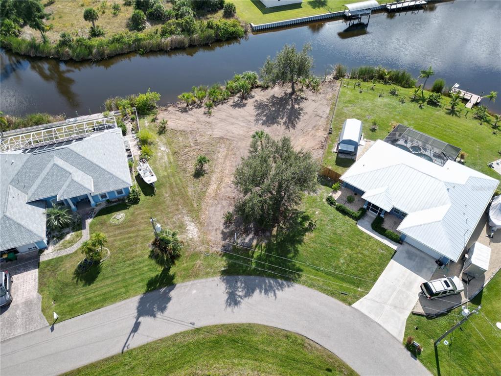 An aerial view shows a vacant waterfront lot situated between two houses on a cul-de-sac — 9588 NASTRAND CIRCLE, PORT CHARLOTTE, FL