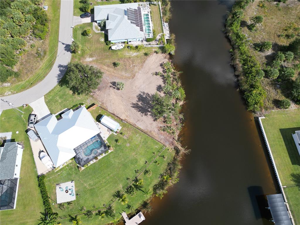 An aerial view shows two waterfront houses with pools and a vacant lot between them — 9588 NASTRAND CIRCLE, PORT CHARLOTTE, FL