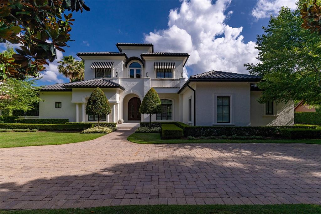 A two-story white stucco house with a tiled roof and a brick paver driveway — 1180 VIA LUGANO, WINTER PARK, FL