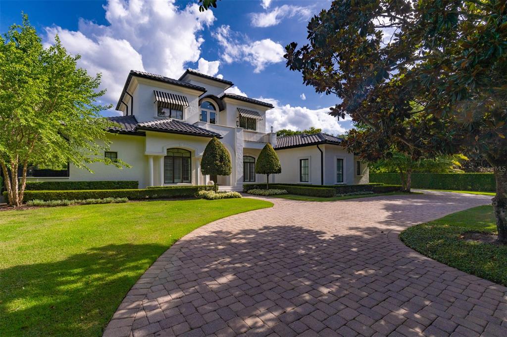 A two-story white house with a tiled roof and a paved driveway under a sky — 1180 VIA LUGANO, WINTER PARK, FL
