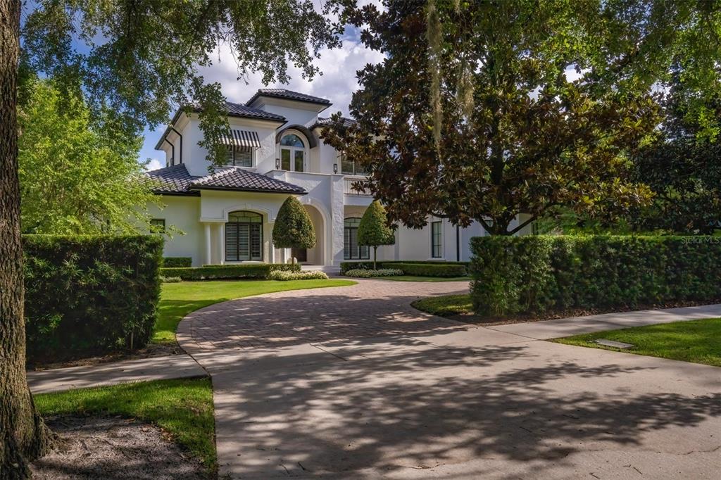 A two-story white stucco house with a tiled roof and a curved brick driveway — 1180 VIA LUGANO, WINTER PARK, FL
