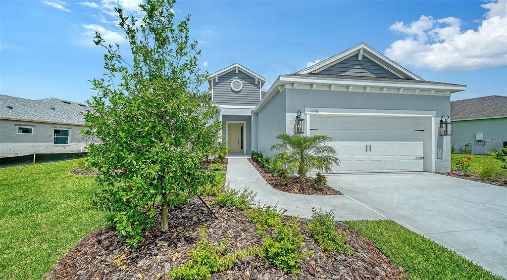 A single-story house with a gray exterior, a two-car garage, and a landscaped front yard — 14406 SKIPPING STONE LOOP, PARRISH, FL