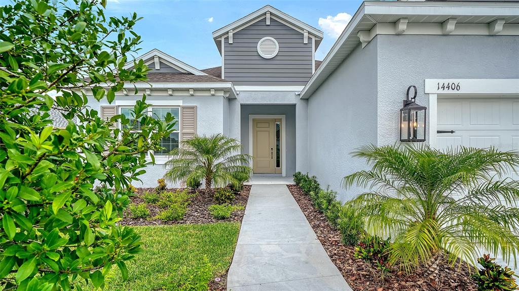 A concrete walkway leads to the front entrance of a light gray single-story house — 14406 SKIPPING STONE LOOP, PARRISH, FL
