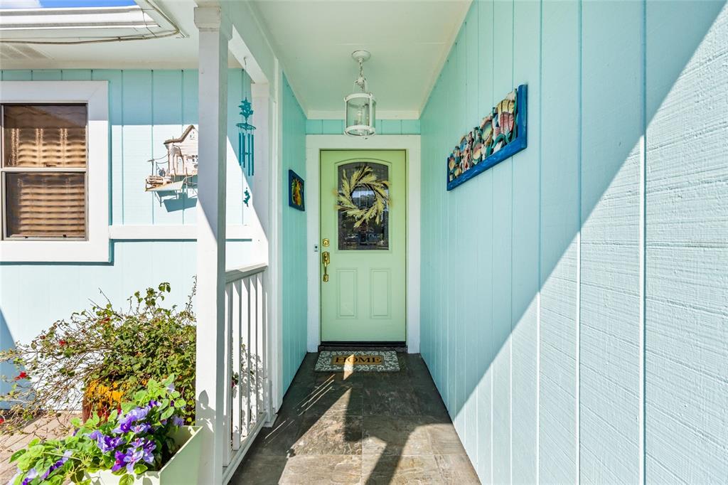 A light blue exterior wall features a pale green front door with a decorative wreath — 6609 MAUNA LOA BOULEVARD, SARASOTA, FL